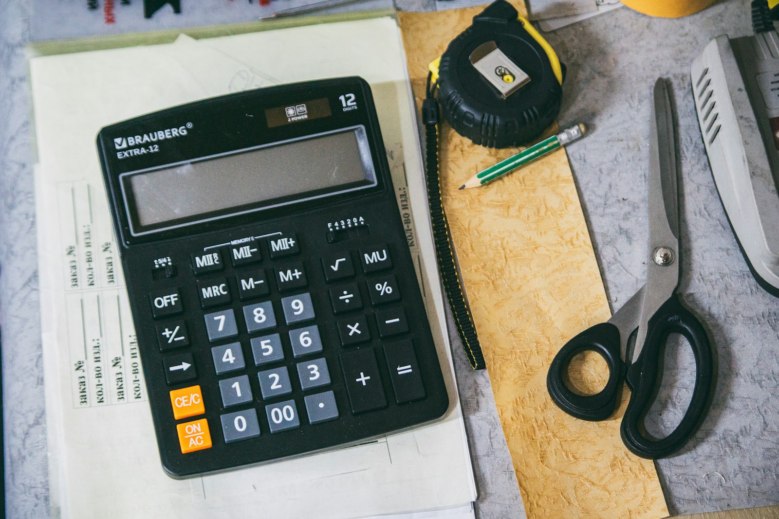 Calculator and contractor tools on a desk — the math on deferred home maintenance always favors the homeowner who runs it sooner.
