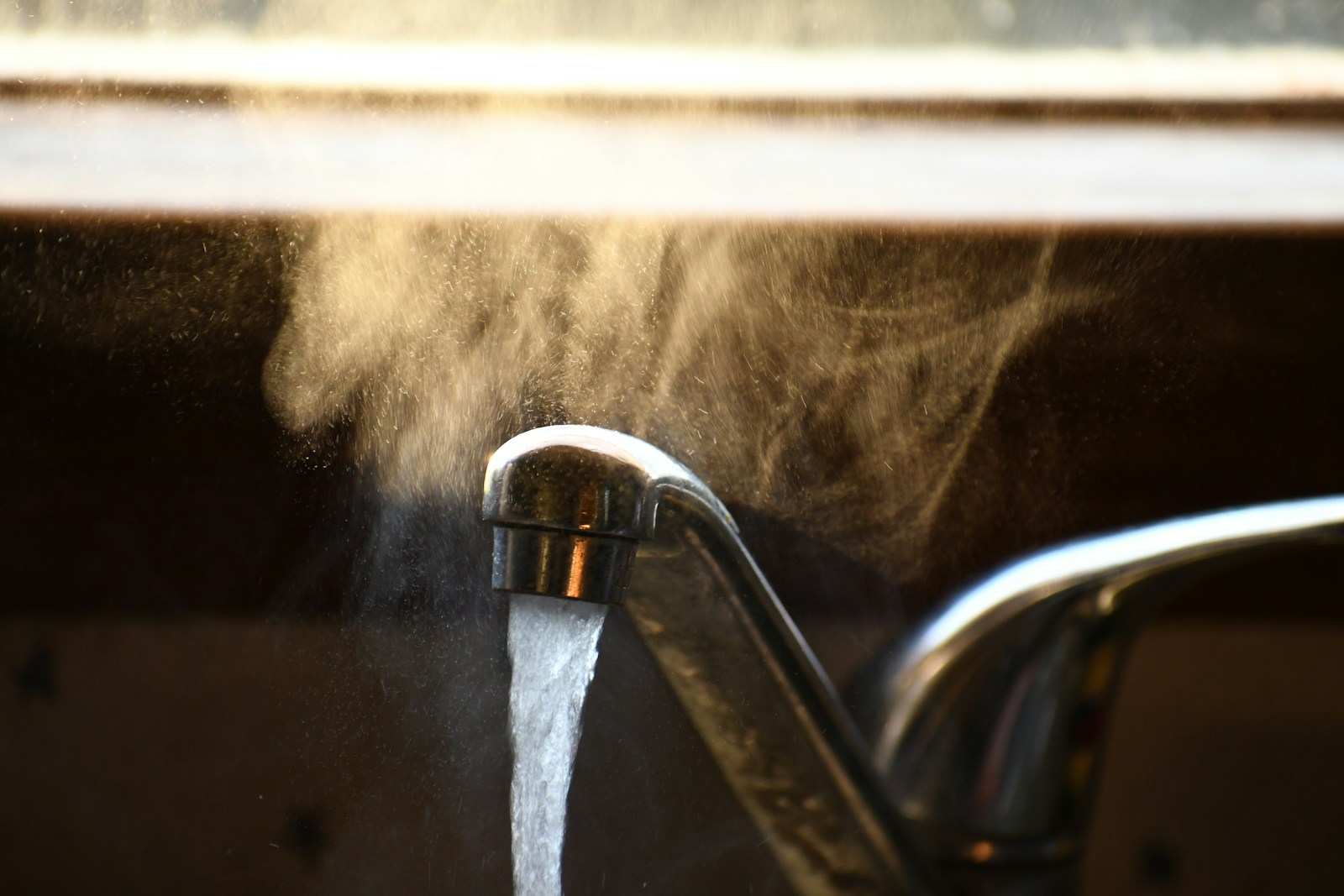 Steam rising from hot water running at a home faucet, the everyday comfort a healthy water heater quietly delivers.